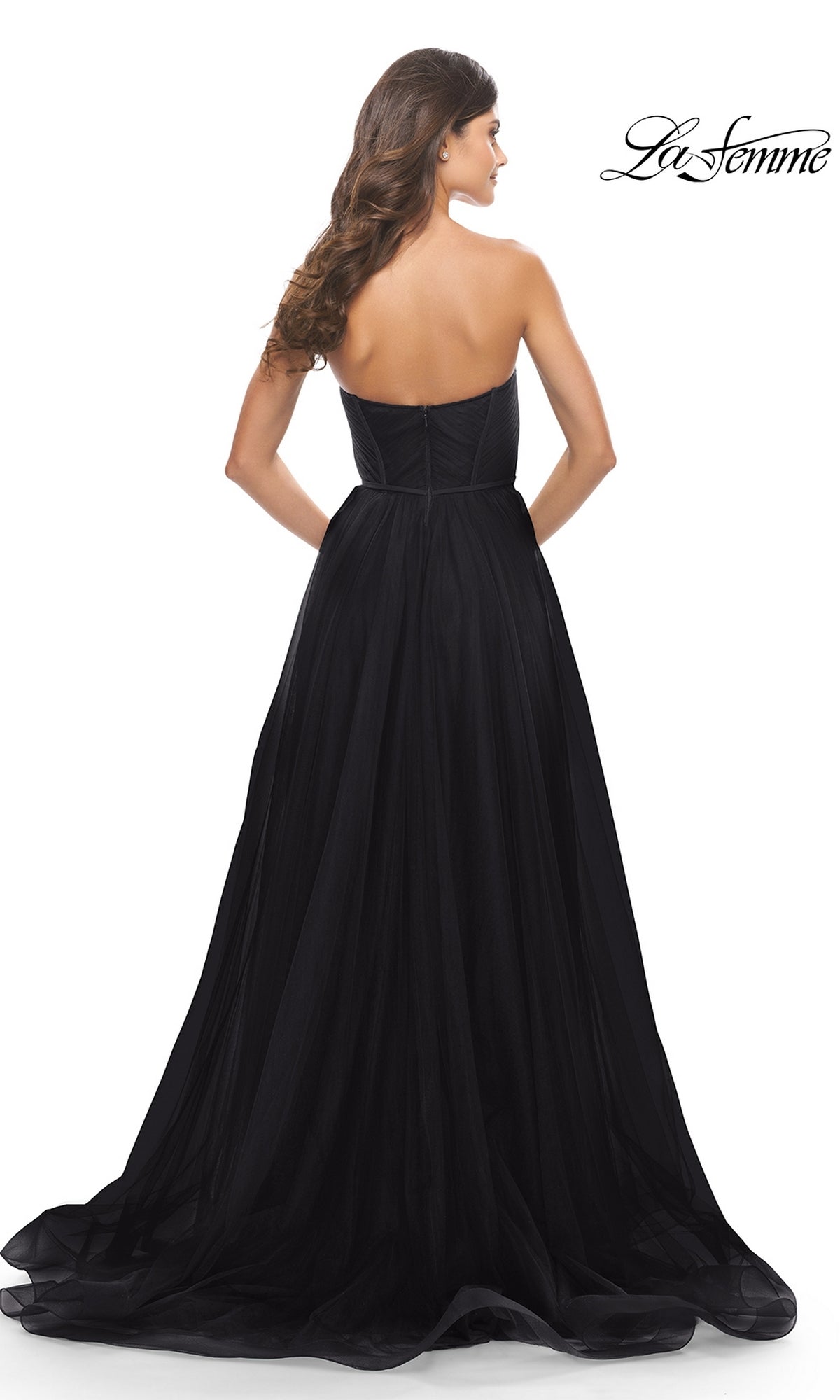 A woman with long brown hair faces away, showcasing the back of the Strapless Long Prom Ball Gown: La Femme 31205. The elegant A-line dress is featured with the La Femme logo in the top right corner.